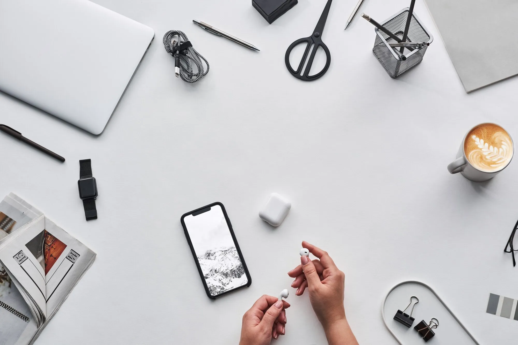Bureau vu de dessus avec ordinateur portable, smartphone, montre connectée, écouteurs et câble de chargeur : les petits appareils du quotidien, ceux qu’on laisse en charge ou en veille, pèsent aussi sur la facture d’énergie