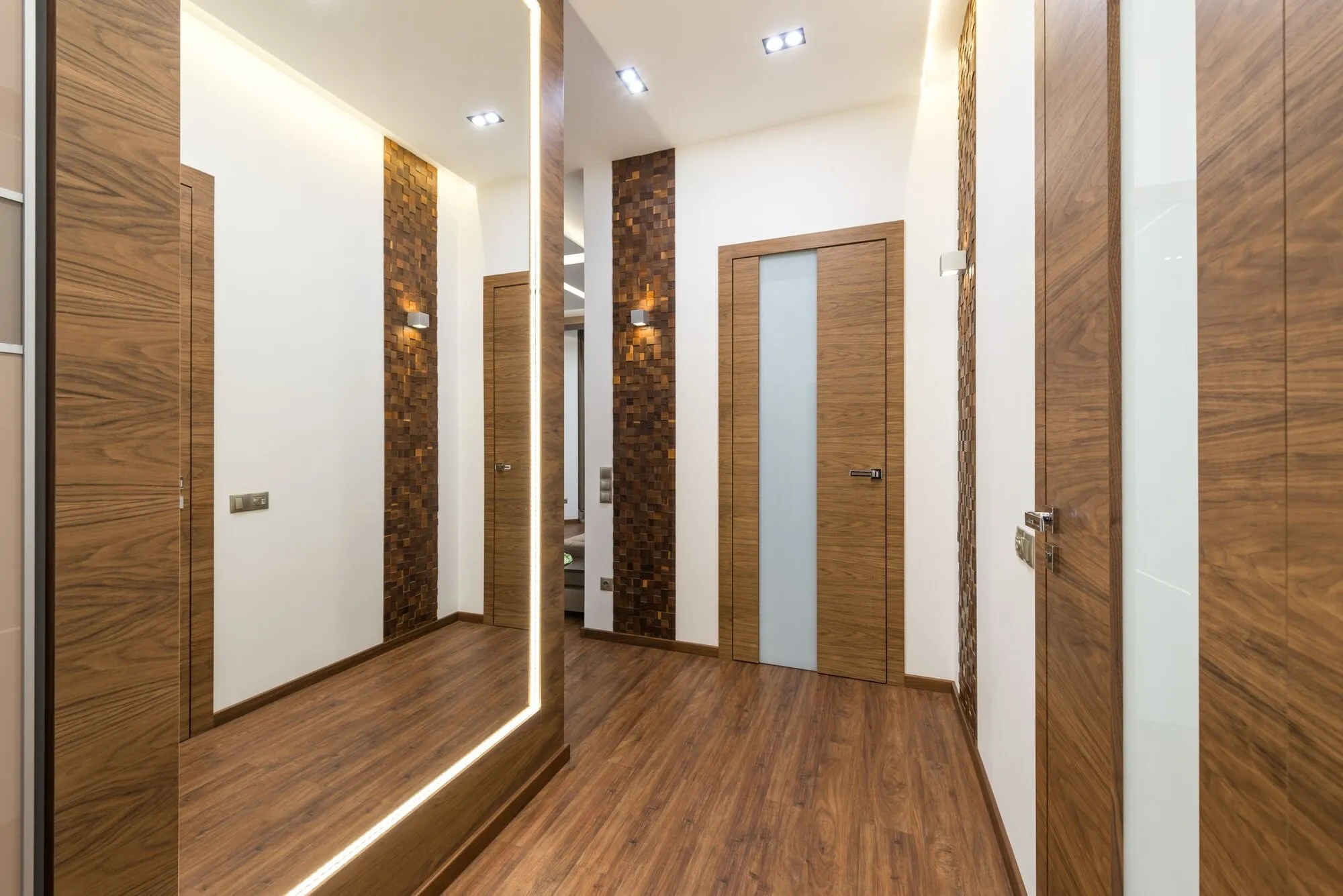 Couloir clair desservant plusieurs portes en bois : autant d’accès distincts que de personnes qui doivent entrer, chacune avec ses propres horaires