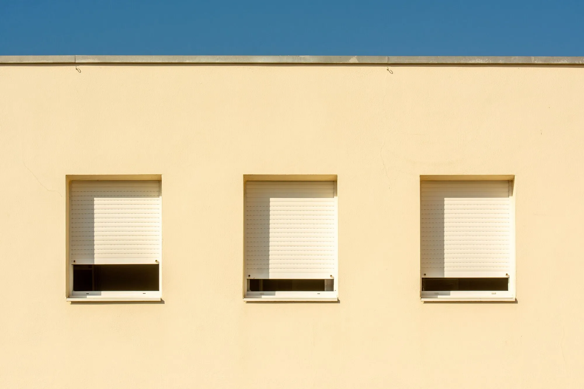 Façade en plein soleil, volets roulants presque fermés : la façade exposée se protège, les autres peuvent rester ouvertes