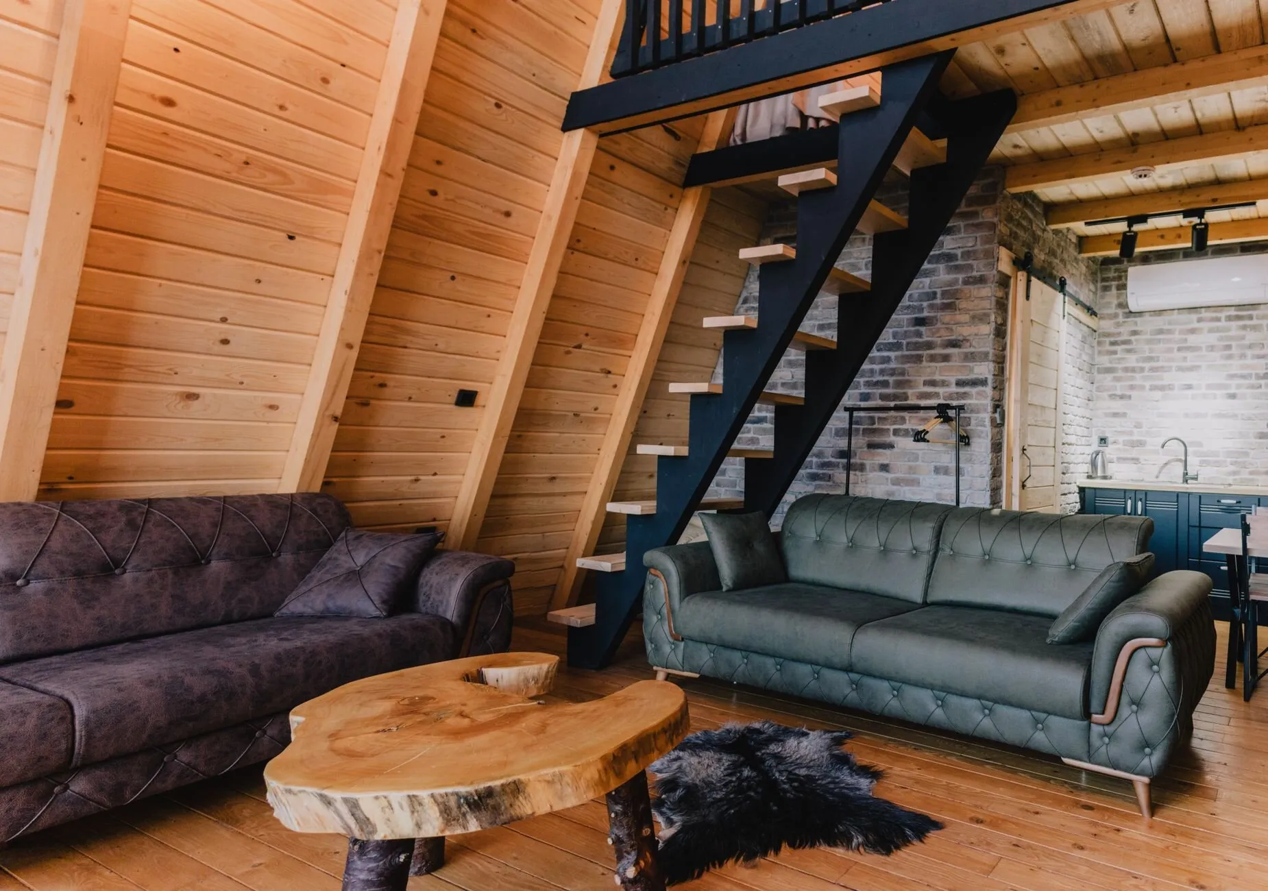 Séjour de chalet tout en bois, canapés et table basse en rondin : le confort d’une installation posée avec le temps nécessaire, avant les premiers froids