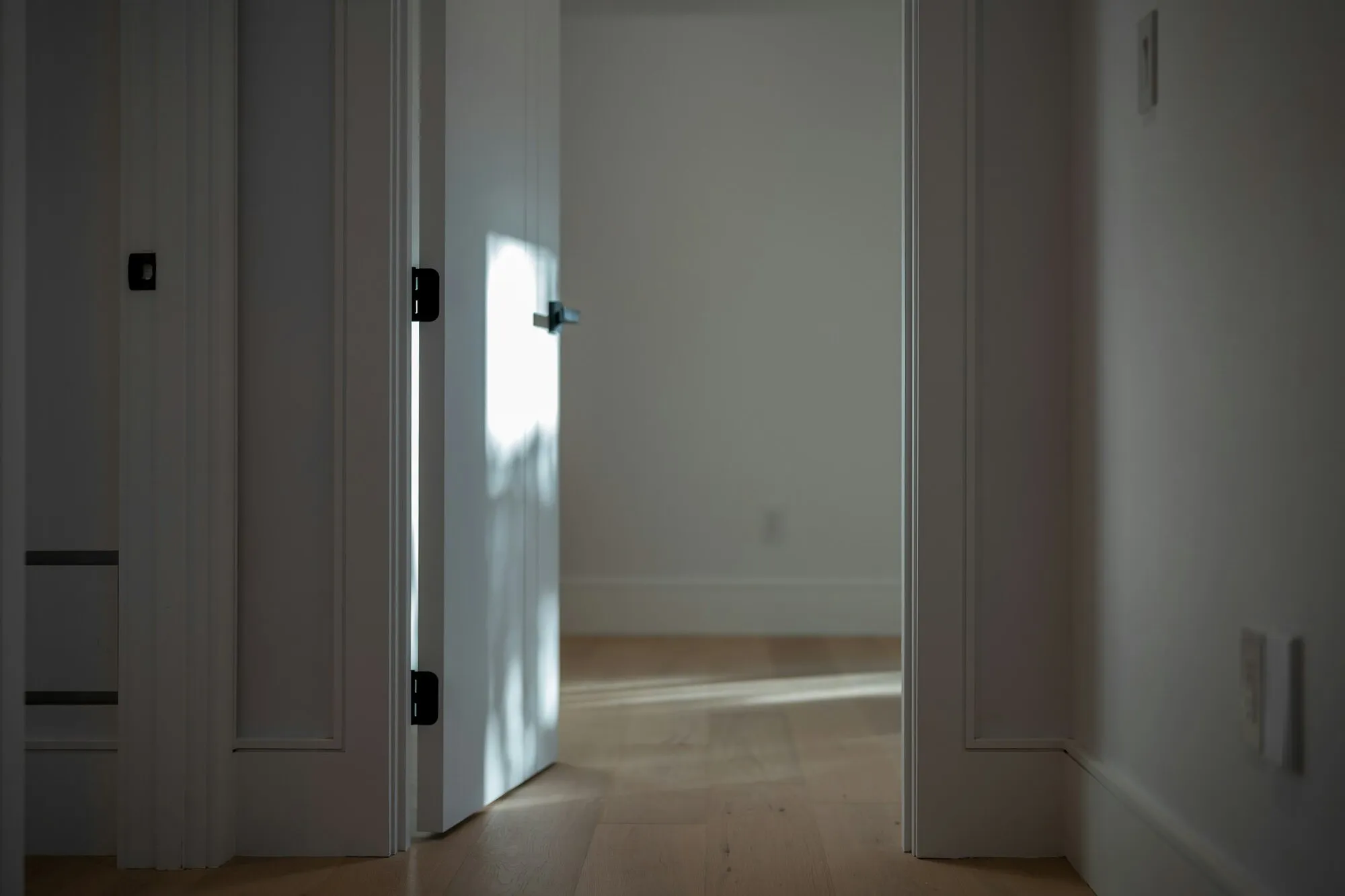 Porte blanche entrouverte sur un parquet clair : les passages et les ouvertures se jugent sur place, une fois la personne rentrée