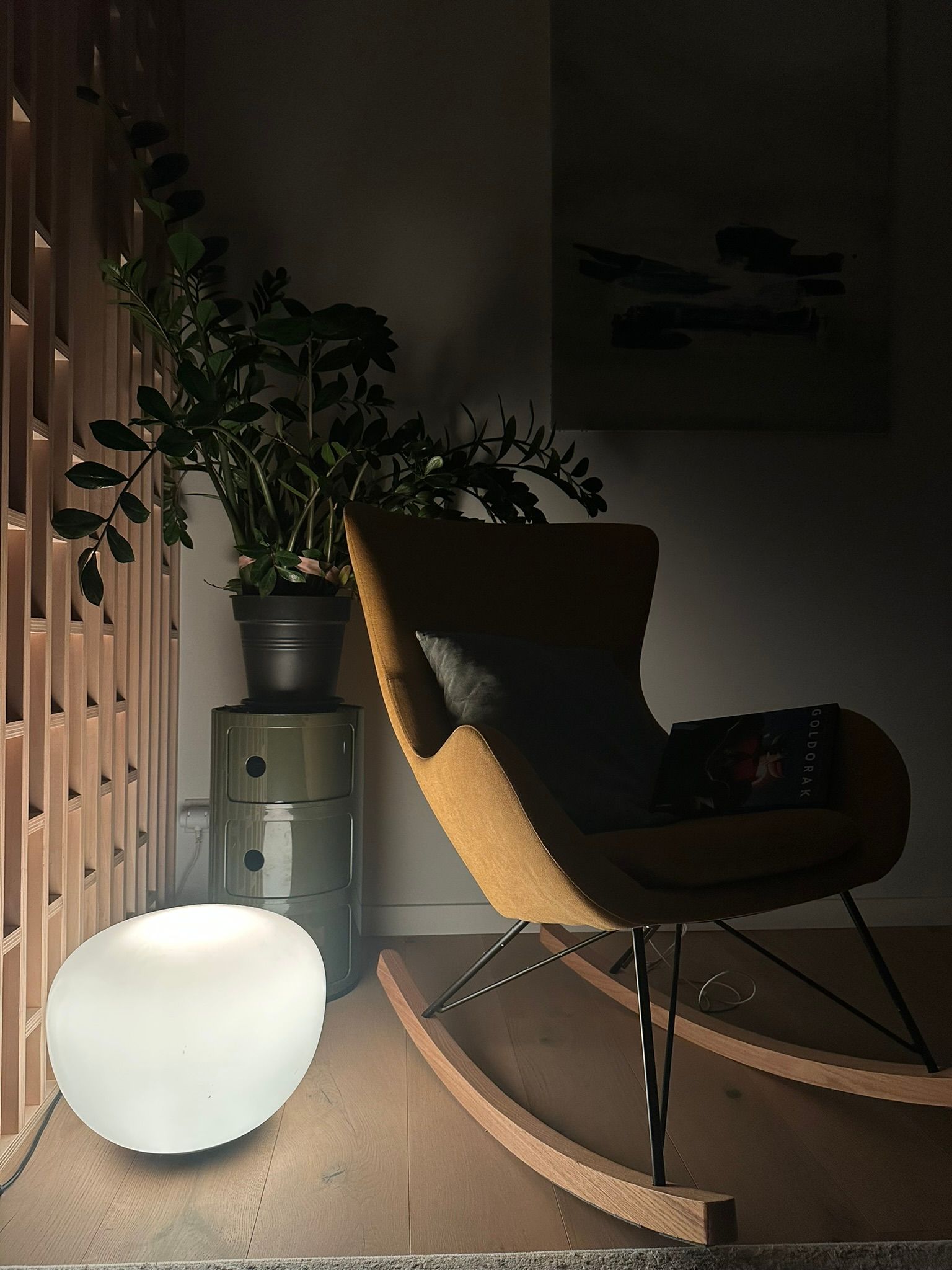 Coin lecture au crépuscule : une lampe d'ambiance allumée près d'un fauteuil à bascule, comme en présence des occupants