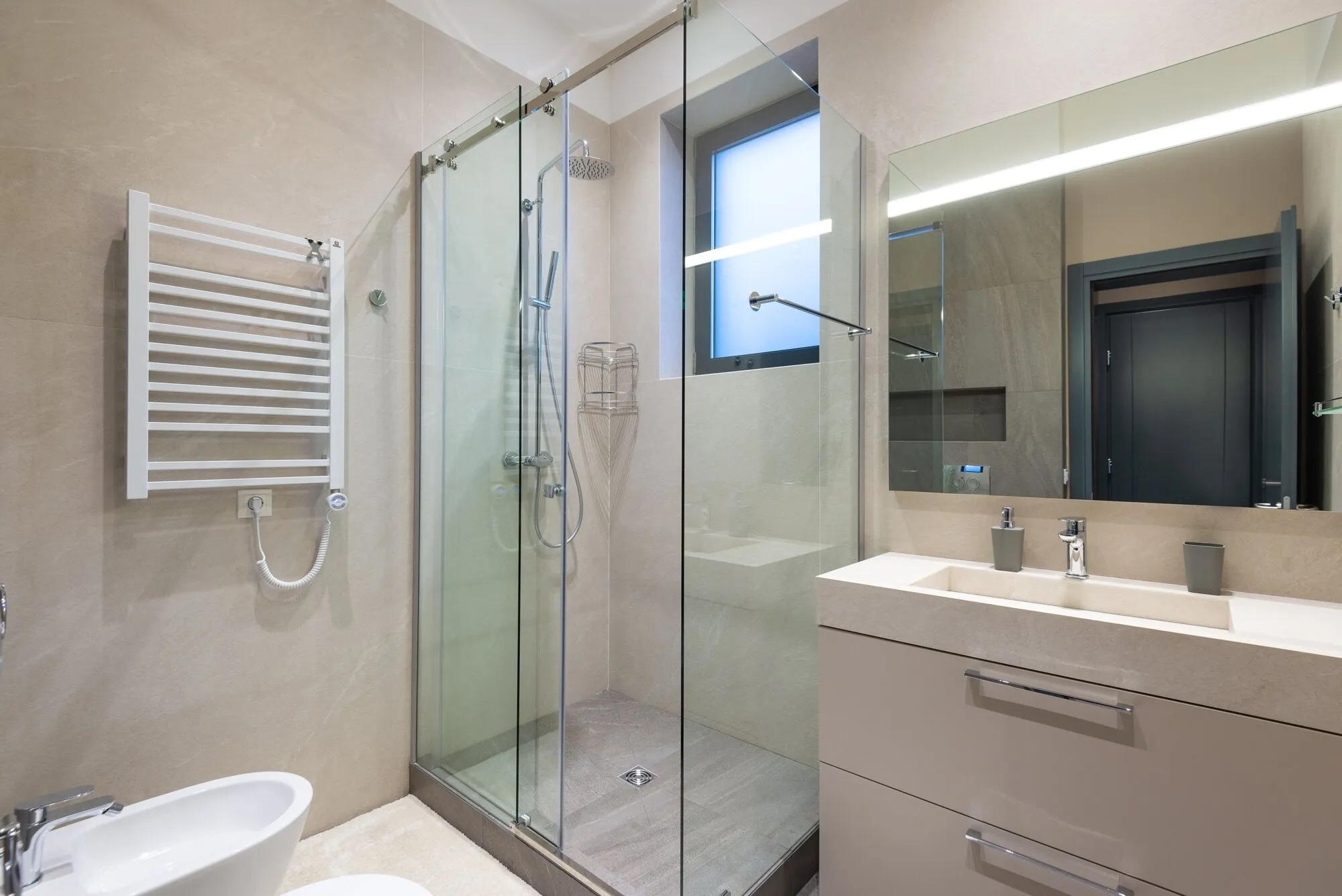 Salle de bain claire, douche fermée par une paroi vitrée : derrière ce verre, un détecteur infrarouge ne voit plus personne